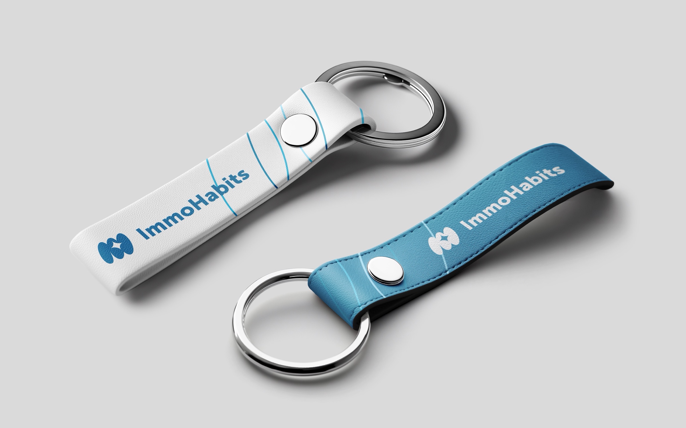 Twee leren sleutelhangers met het logo, in wit en blauw